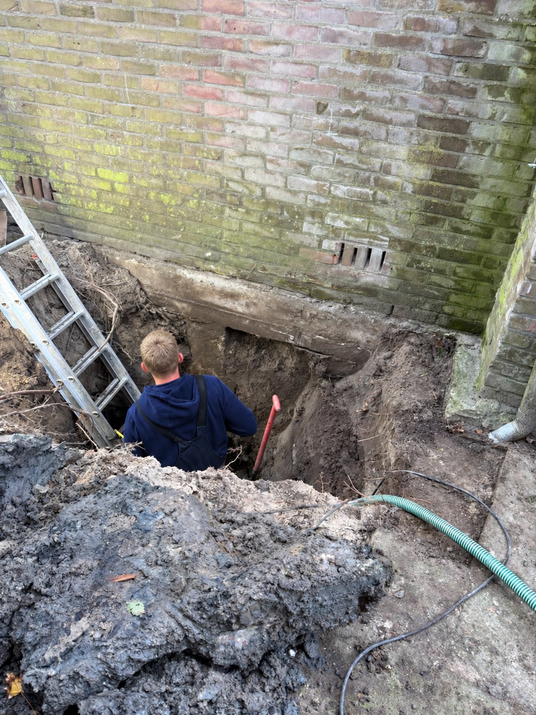 Inspectiesleuf naast een woning tijdens een funderingsonderzoek