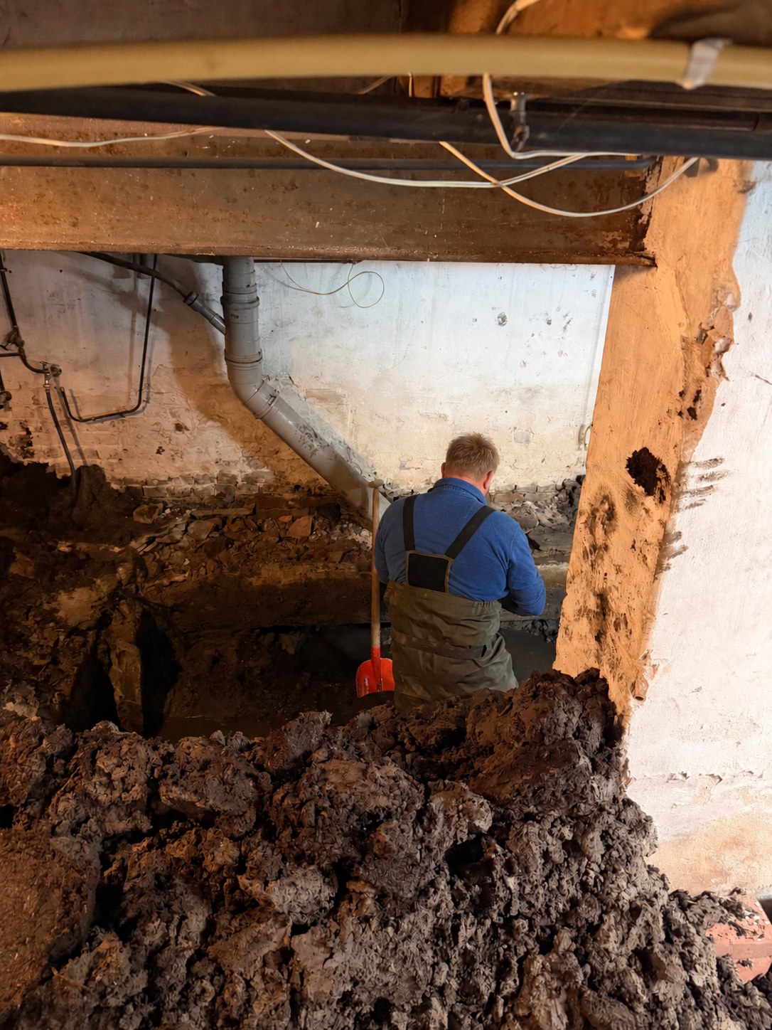 Funderingsonderzoek: een inspecteur graaft de fundering onder een woning bloot